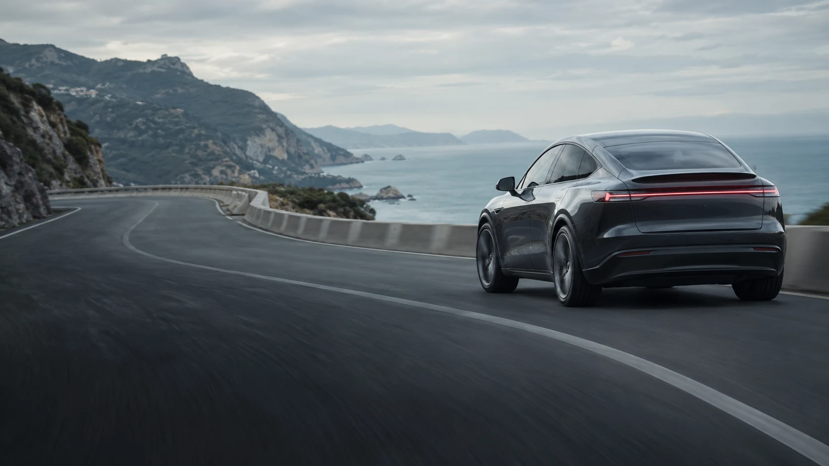 A graphite electric vehicle on a sweeping coastal road